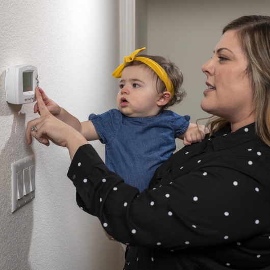 mom and baby adjust thermostat